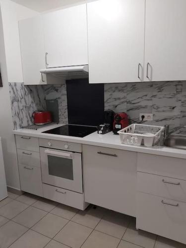 une cuisine avec des armoires blanches et un four à plaques de cuisson dans l'établissement Au coin du souffle 3 pièces au pied du Tram T2, à Bezons