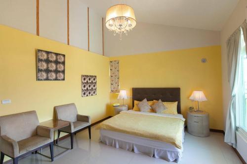 a bedroom with a bed and two chairs and a chandelier at Pure Farm B&B No0856 in Zhuangwei