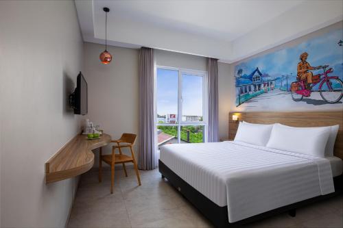 a bedroom with a bed and a desk and a window at favehotel Sidoarjo in Sidoarjo