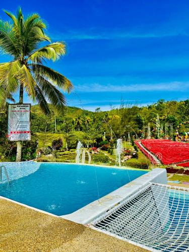 a swimming pool with a palm tree and a fountain at Jardin De Ysabelle in Tagpupungan