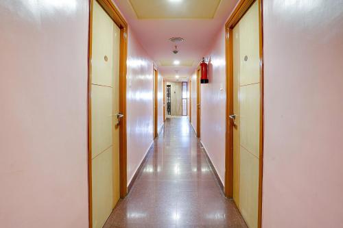 un long couloir avec des murs blancs, du parquet et des plafonds marron dans l'établissement OYO Shanthaa Residency, à Surūrnagar