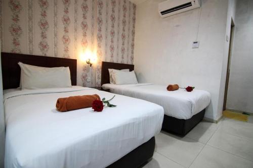 two beds in a hotel room with flowers on them at Rose Cottage Hotel Taman Perling in Johor Bahru