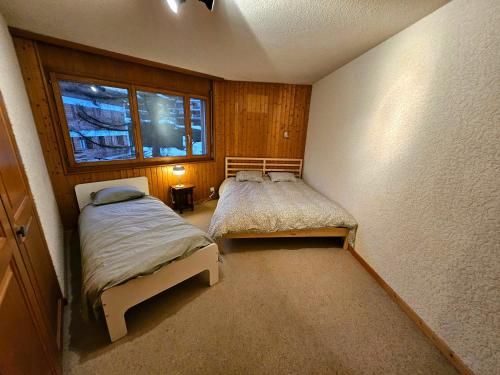韋爾比耶的住宿－Verbier Appartement Andrea，一间卧室设有两张床和窗户。