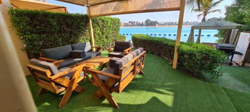 eine Terrasse mit Stühlen, Sonnenschirm und Wasser in der Unterkunft درة العروس شاليه شاطئ البرادايس in Durrat Al-Arus