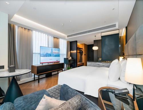 ein Hotelzimmer mit einem großen Bett und einem Flachbild-TV in der Unterkunft Intercity Wuhan CADE Optics Valley in Wuhan