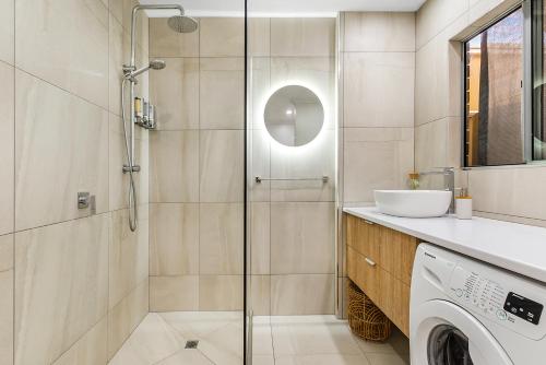 a bathroom with a shower and a washing machine at Comfortable & Convenient Coastal Studio in Maroochydore