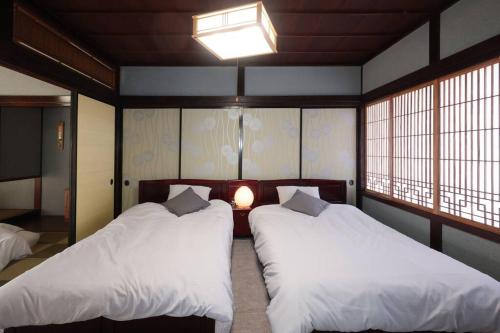 2 camas en una habitación con 2 ventanas en くつろぎのお宿「やわや」, en Himi