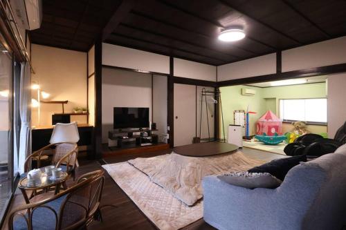 Una sala de estar con un sofá azul y un televisor. en くつろぎのお宿「やわや」, en Himi