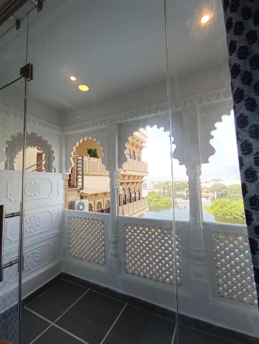 a bathroom with a glass shower with a view of a building at Hotel Mewari Villa PURE VEG in Udaipur