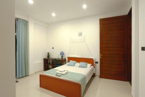 1 dormitorio con 1 cama y puerta de madera en Anu - The Breeze of Heaven, en Kandy