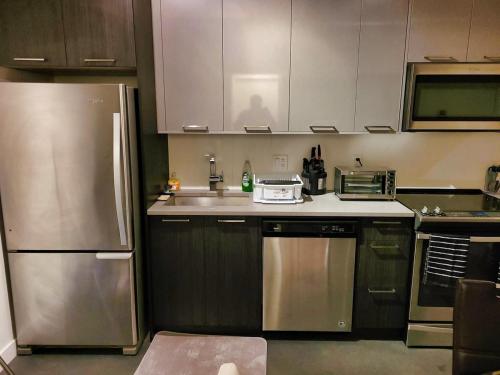 a kitchen with a stainless steel refrigerator and cabinets at 1 Bedroom with Balcony in Calgary