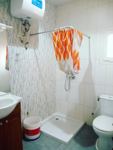 a bathroom with a toilet and a shower with an umbrella at Residence Jardin Tropical in Yaoundé