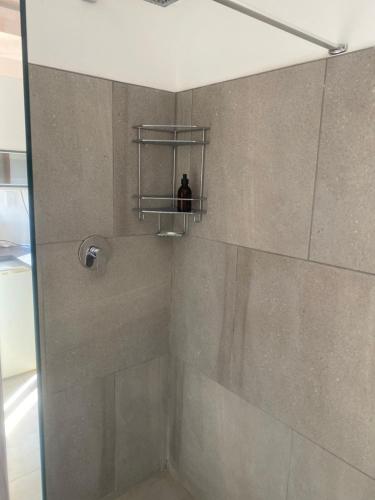 a bathroom with a shower with a shelf on the wall at Khomas Hochland Chalet in Prospect