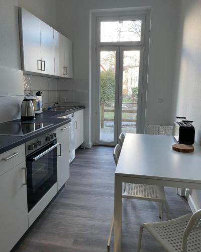 een keuken met witte kasten en een tafel en stoelen bij 3 Zimmer für 4 Personen - große Dachterrasse in Bremen