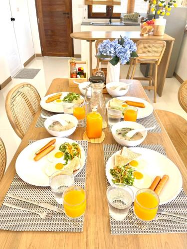 a table with plates of food and glasses of orange juice at บ้านข้าวหอม บึงโขงหลง in Ban Sok Pho