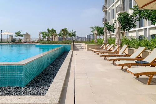 a row of chaise lounge chairs next to a swimming pool at Frank Porter - Collective Tower 1 in Dubai