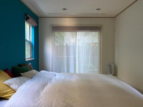 een slaapkamer met een groot wit bed voor een raam bij Kamakura vacation house - Vacation STAY 15361 in Kamakura