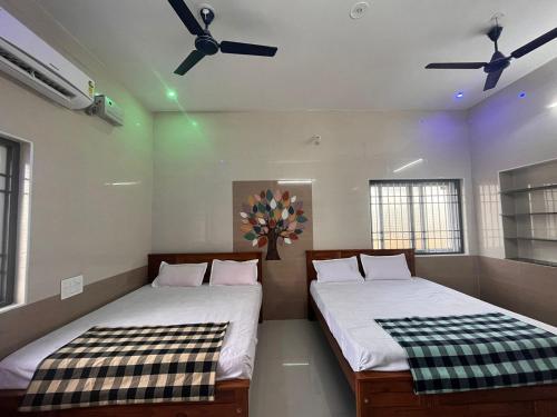 two beds in a room with two windows at MOHAN COTTAGE in Wodapatti