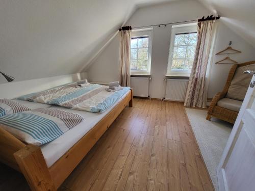 a bedroom with a bed and a chair and windows at Nörderland in Norden