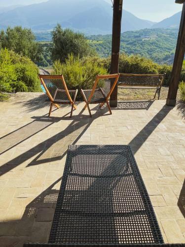 two benches sitting on a patio with a view at Pietra Pizzuta Country House in Torre deʼ Passeri