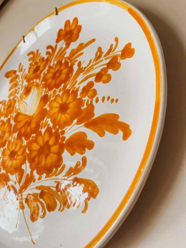 a white plate with orange flowers painted on it at Pietra Pizzuta Country House in Torre deʼ Passeri
