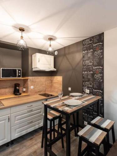 - une cuisine avec une table, des chaises et un tableau noir dans l'établissement L'Atelier- appartement cosy avec cour - centre, à Bourgoin-Jallieu