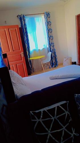 1 dormitorio con 2 camas y ventana con silla en Studio 23, en Mombasa