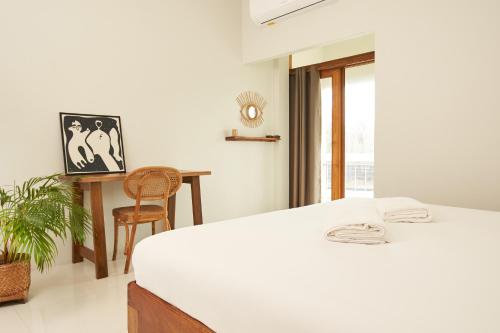 a white bedroom with a bed and a desk at Imm Paknham in Ban Hin Sam Kon