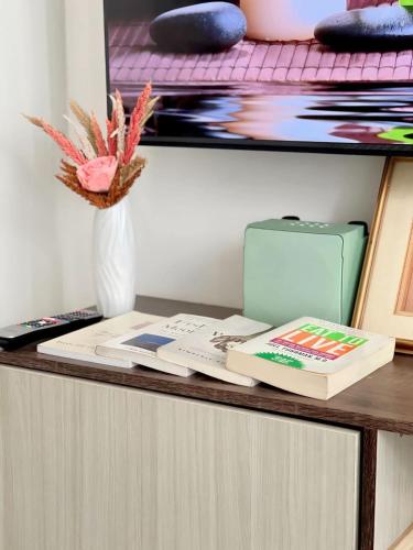 een bureau met een boek en een vaas met bloemen bij A3J Staycation at Azure Urban Resort Residences in Manilla