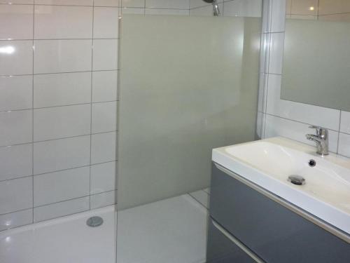 ein weißes Bad mit einem Waschbecken und einer Dusche in der Unterkunft Résidence ORR DES FORETS - Studio pour 4 Personnes 794 in Les Orres