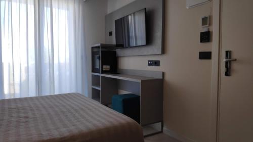 里喬內的住宿－Hotel Ascot Riccione，一间卧室配有一张床,墙上配有电视