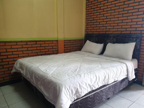 a bed with white sheets and pillows in a room at Bromo Holiday Guest House in Ngadisari