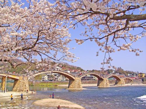 a bridge over a river with people standing in the water at KAMENOI HOTEL Setouchi Hikari in Hikari