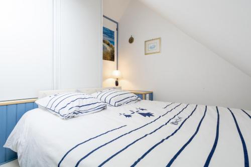 una cama blanca con almohadas a rayas encima en Appartement Guillaume, en Trégunc