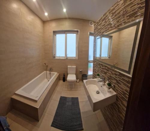 La salle de bains est pourvue d'une baignoire, de toilettes et d'un lavabo. dans l'établissement Modern 3BR Apartment in Swieqi, à Is-Swieqi
