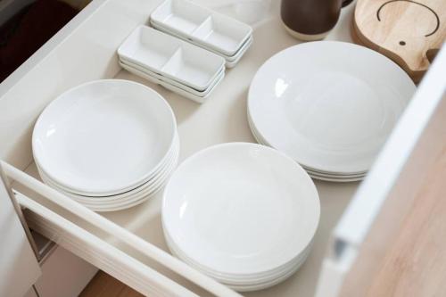 three white plates on a shelf in a drawer at エメラルド色に輝く希望ヶ丘ビーチまで徒歩圏内！リゾート地恩納村のお洒落な3LDK一軒家貸し切り！ in Inbu