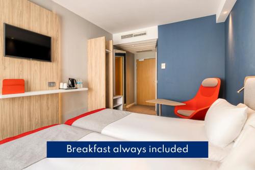 a bedroom with a bed and a tv and a chair at Holiday Inn Express Mechelen City Centre, an IHG Hotel in Mechelen