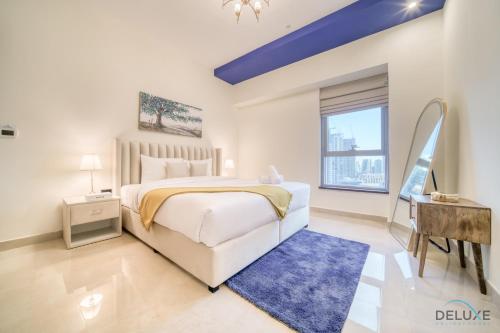 a white bedroom with a bed and a blue rug at Spacious 3BR with Assistant’s Room at West Heights 4 Business Bay by Deluxe Holiday Homes in Dubai