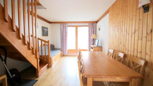 une salle à manger avec une table en bois et un escalier dans l'établissement Résidence Parc Aux Etoiles - PARC AUX ETOILES -CH07- AVEC PISCINE ET SAUNA-Chalet dup MAE-2214, à Narreyroux