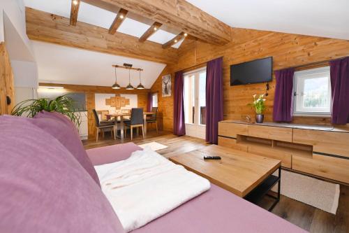 a living room with a purple couch and a table at Chalet Claudia in Bartholomäberg