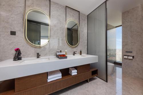 een badkamer met 2 wastafels en 2 spiegels bij UrCove by Hyatt Foshan Downtown in Foshan