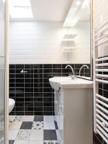 - une salle de bains en noir et blanc avec lavabo et toilettes dans l'établissement Le Paris Eiffel - Appartement Cosy en plein centre, à Bourgoin-Jallieu