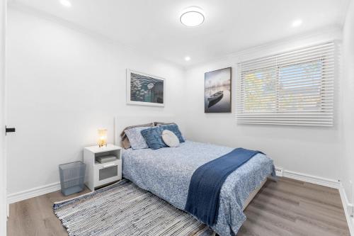 a white bedroom with a bed and a window at Beautiful and quiet urban cabin in Montreal