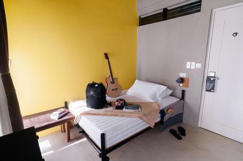 a room with a bed with a guitar on it at Spin Designer Hostel - El Nido in El Nido