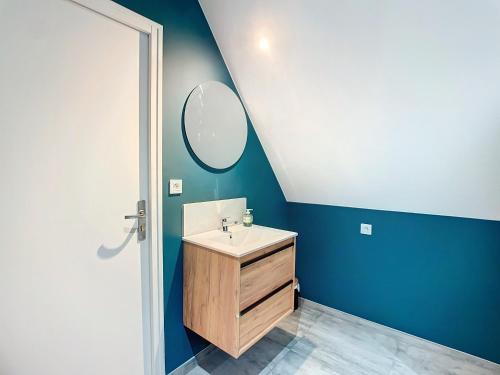 une salle de bain avec un lavabo et un miroir dans l'établissement Maison de vacances en famille, à Agon-Coutainville