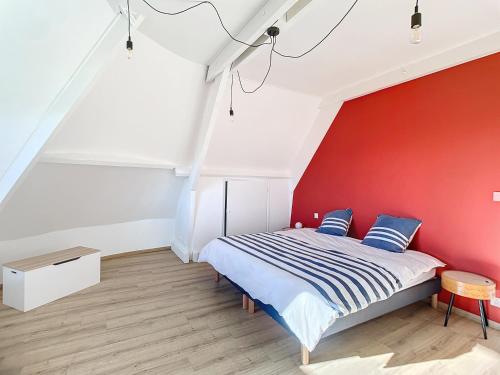 - une chambre dotée d'un mur rouge et d'un lit avec des oreillers bleus dans l'établissement Maison de vacances en famille, à Agon-Coutainville
