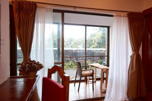 a living room with a large window and a table and chairs at Brookside Villa Pokhara in Pokhara