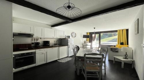 une cuisine avec des armoires blanches et une table et des chaises dans l'établissement Résidence Pendine 1 - P907 - Appt T2/Coin montagne - 6 personnes - Centre st 144, à Les Prés