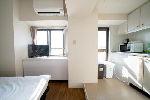 a small white kitchen with a microwave and a sink at Nishinippori Guest House in Tokyo