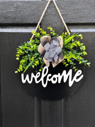 a welcome sign hanging on a wall with a plant at City Euphoria in Portsmouth